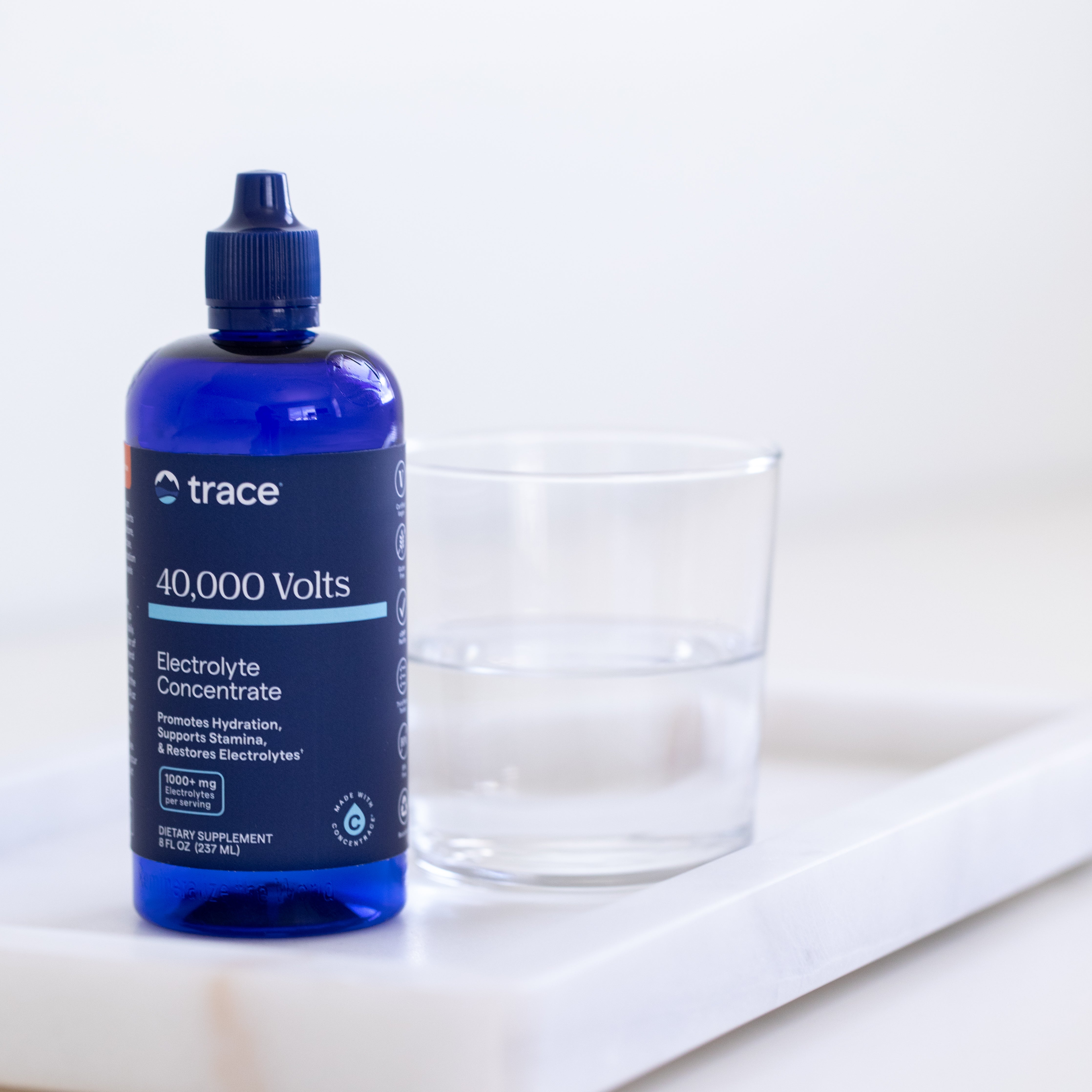 Trace minerals 40 000 Volts elektrolitų pakuotė ant stalo su stikline vandens